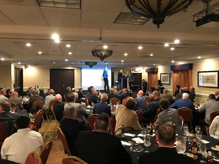 A large group of people gathered for the national technical meeting facing a presenter